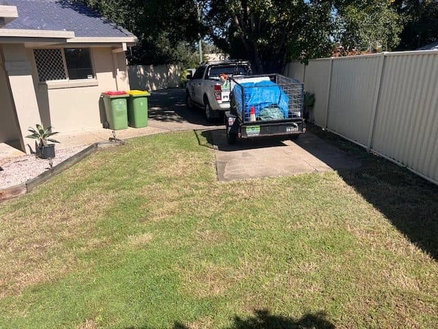Ute and trailer on a driveway beside a mown lawn